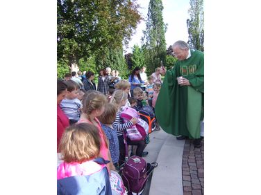 Pfarrer Vonderau segnet einzeln jeden Schulranzen und Kindergartenrucksack